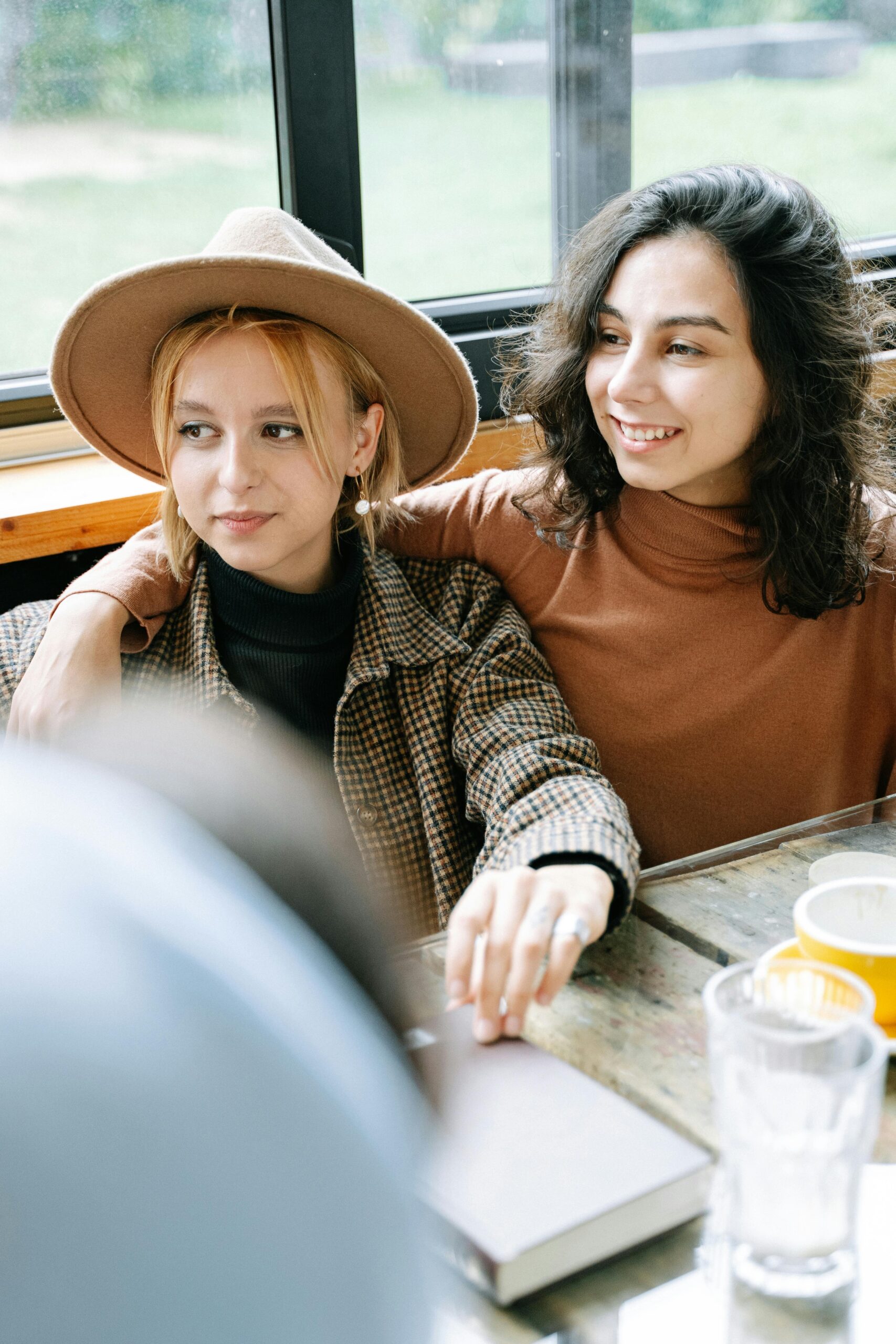 Two young women in casual attire enjoy a relaxed moment indoors, capturing friendship and warmth.